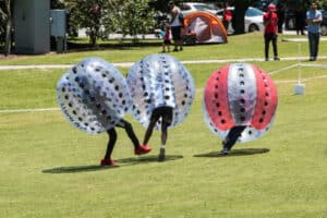 Kinderen spelen bumper voetbal met grote opblaasbare ballen in park.