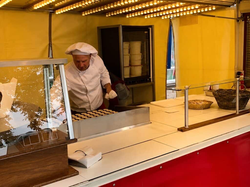 Clown Snoepy poffertjeswagen met chef in witte outfit en keukenapparatuur.