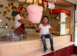 Clown Snoepy serveert grote roze suikerspin en popcorn aan meisje.
