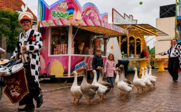 Clown Snoepy met kinderen en ganzen bij een kermis tijdens de Parade.