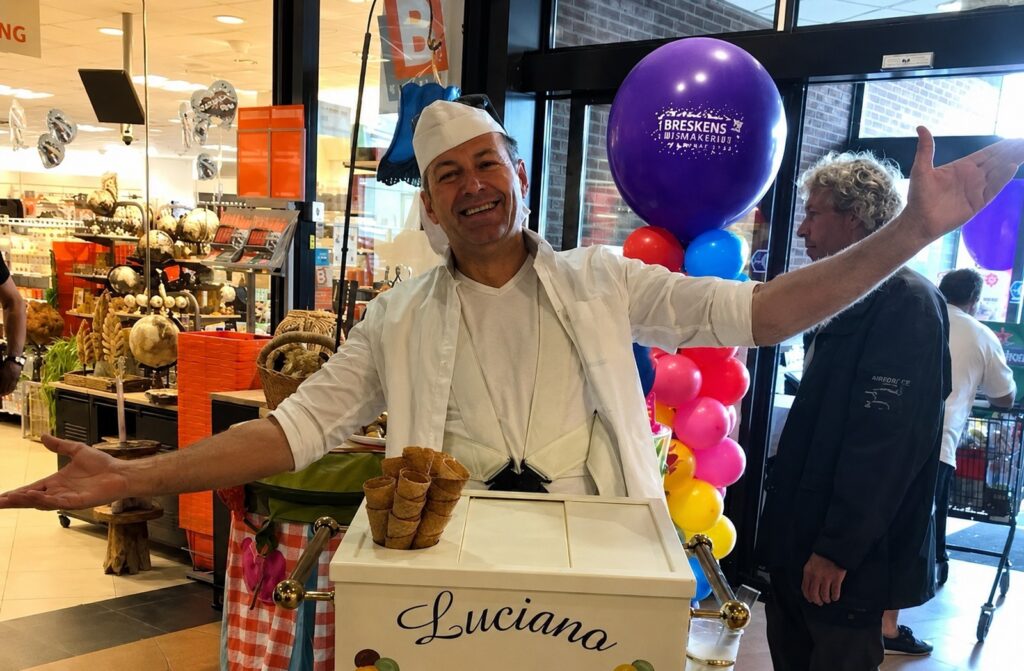 Clown Snoepy serveert ijs met een grote glimlach in een winkelcentrum.