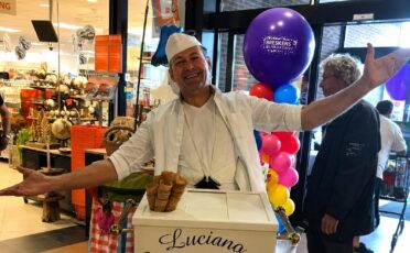 Clown Snoepy serveert ijs met een grote glimlach in een winkelcentrum.