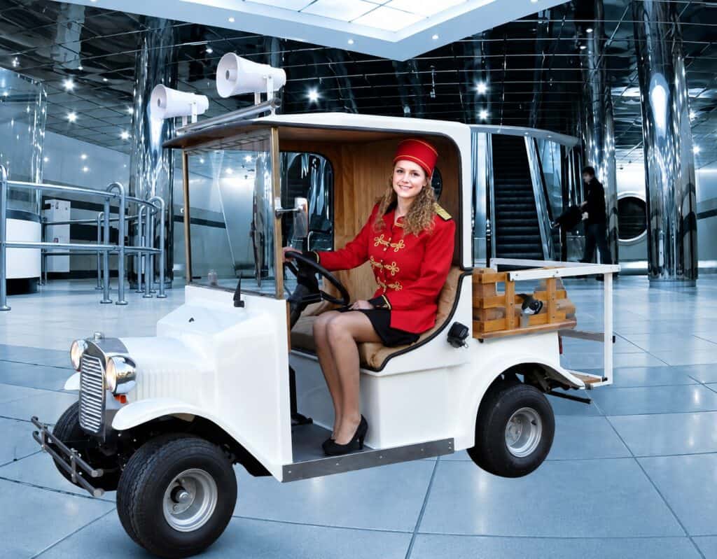 Clown Snoepy in een witte golfkar met rode outfit en hoed.
