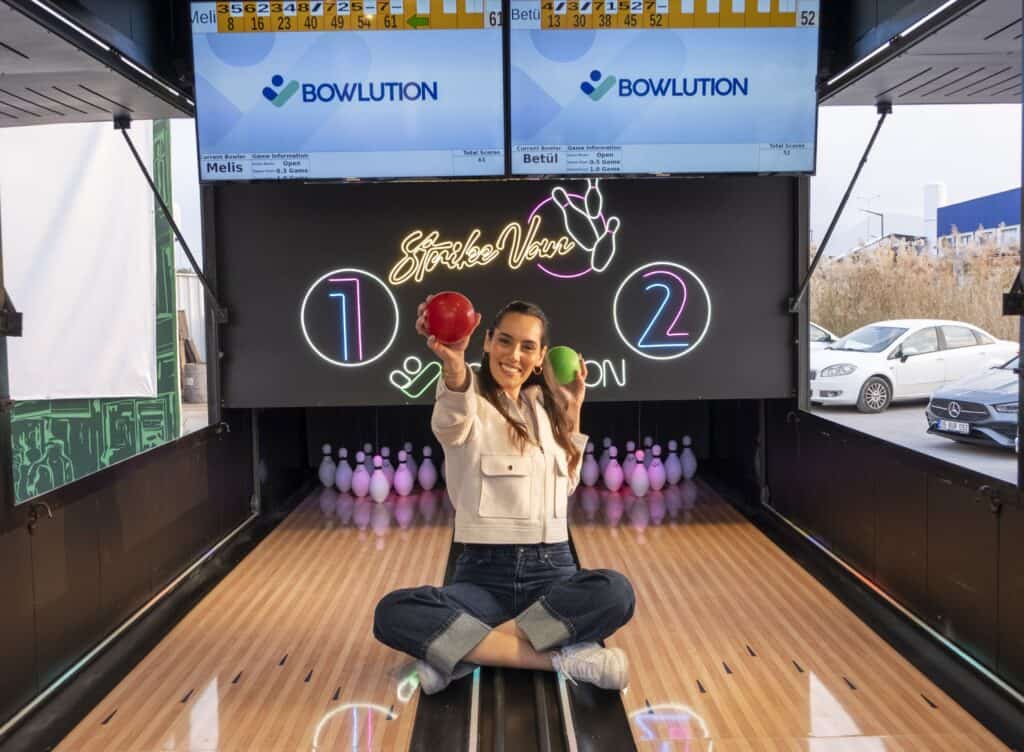 Vrolijke vrouw met bowlingbal op een mobiele bowlingbaan.