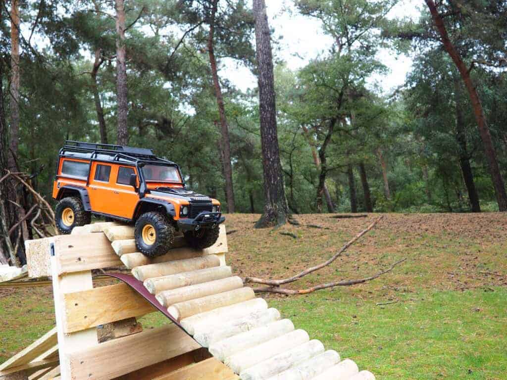 Miniatuur RC auto op houten parcours in bosrijke omgeving.