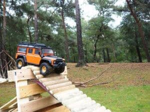 Miniatuur RC auto op houten parcours in bosrijke omgeving.
