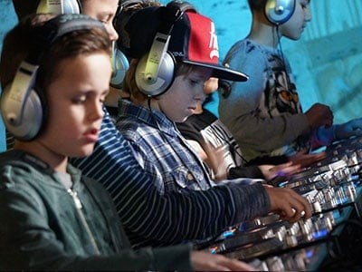 Kinderen draaien muziek met koptelefoons tijdens DJ-activiteit.